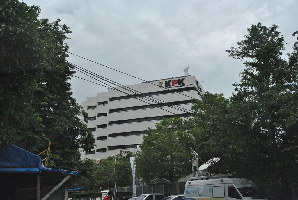 Gedung Komisi Pemberantasan Korupsi dengan fasad kaca dan halaman parkir