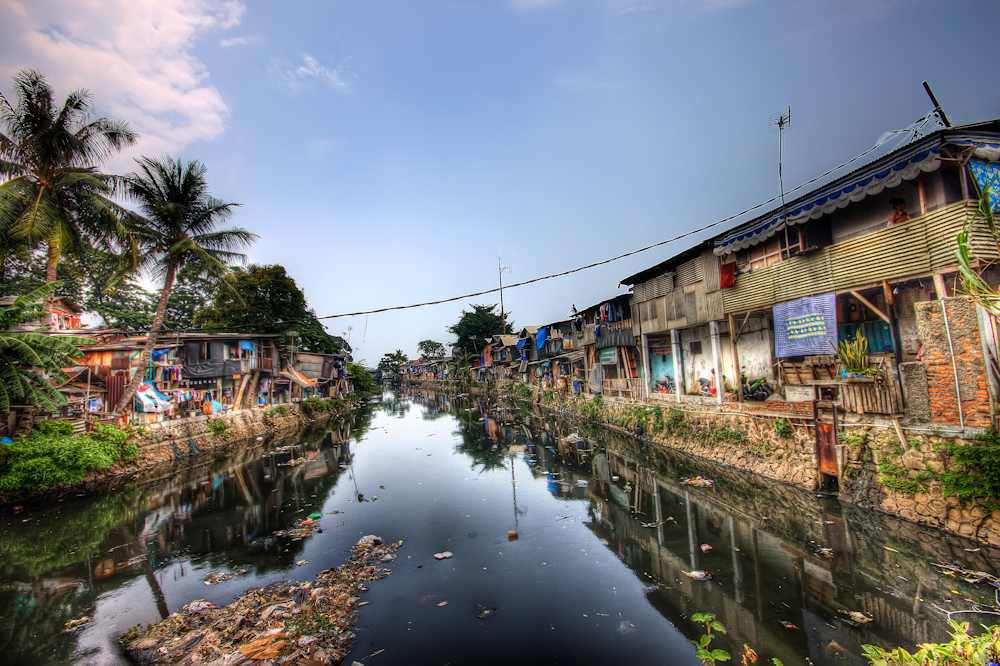 Ilustrasi permukiman padat di tepi kanal Jakarta dengan rumah tidak layak huni