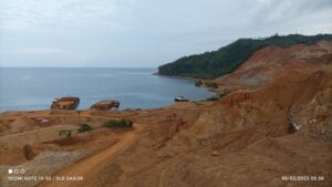 Kawasan penambangan bijih nikel di Kolaka Utara, Sulawesi Tenggara, dengan tumpukan tanah laterit dan tongkang di pesisir