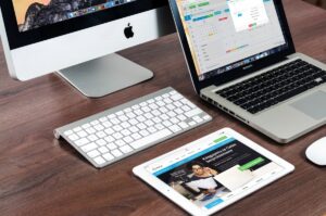 Laptop MacBook dengan layar menyala di atas meja kerja