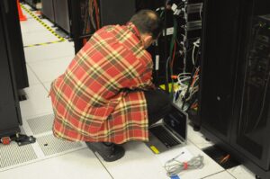 Teknisi bekerja pada rak server di pusat data